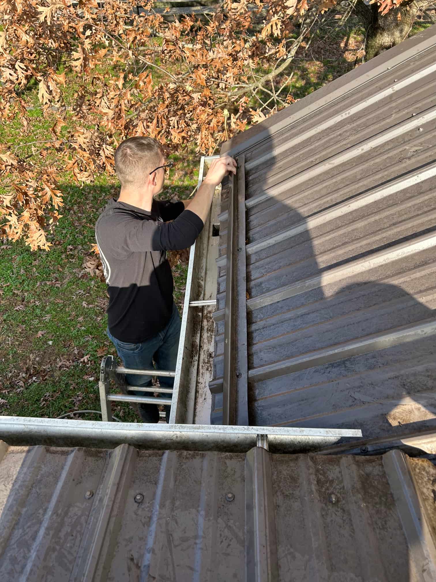 BrightEdge team cleaning gutters on ladder